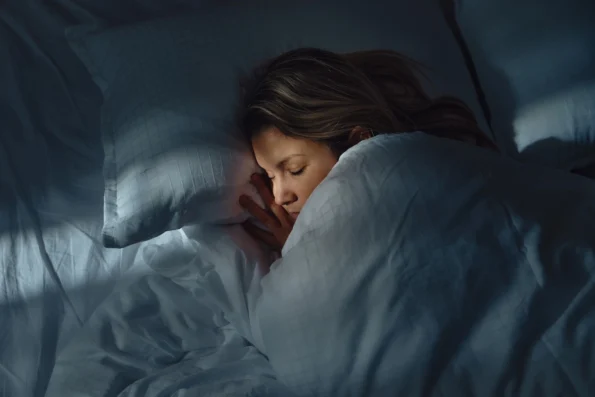 Woman peacefully sleeping in a cozy bed at night, highlighting the importance of quality sleep for natural hormone balance.